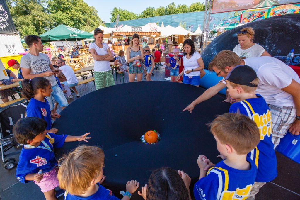 Wetenschapper educeert kinderen over planeten via grote bal op een tafel