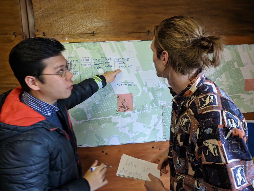 Een jongen wijst naar een kaart en legt iets uit aan een andere student